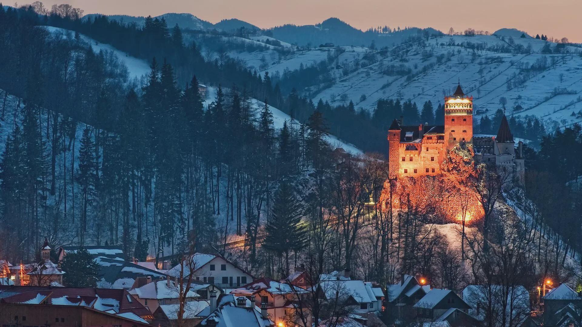 Bran Castle in winter with snow on the battlements and surrounding mountains