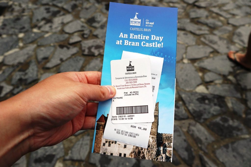 Hand holding an official Bran Castle (Castelul Bran) entry ticket and brochure