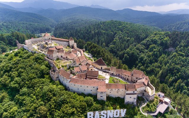 Râșnov Fortress aerial view with the iconic RASNOV letters on the hillside